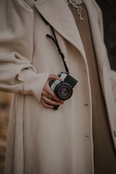 Close-up of a woman holding a vintage camera, showcasing an elegant and timeless fashion style.