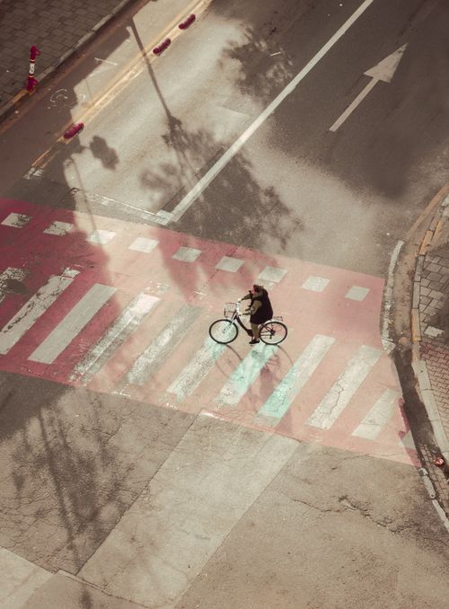 Free A cyclist crosses a city street at a crosswalk in Tirana, Albania. Captured from above. Stock Photo