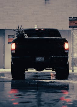 A pickup truck with visible tail lights and a Christmas tree in snowy Vancouver at night.
