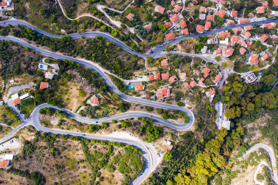 An aerial view of winding roads traversing the lush landscape and scattered houses in Evritania, Greece.