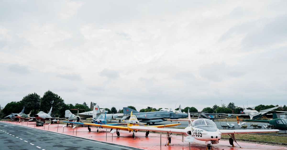 A range of aircraft on display at an outdoor airfield under cloudy skies.