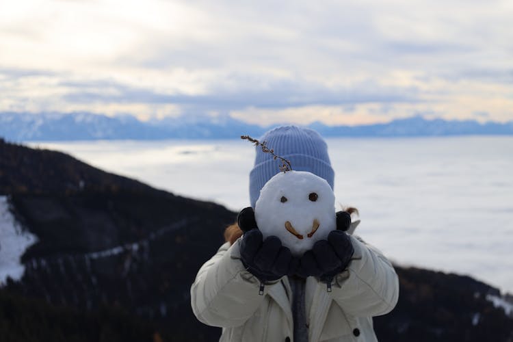 A Kid Holding A Snowman Head