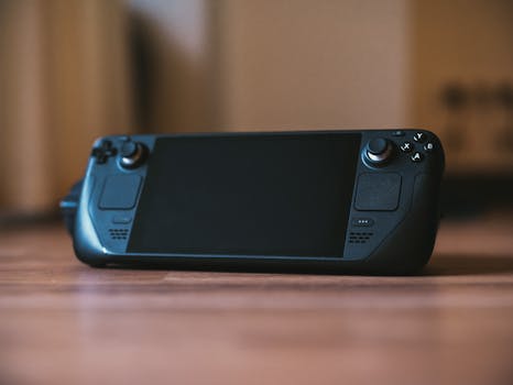 Modern handheld gaming console with buttons and joystick on a wooden surface, ideal for portable gaming enthusiasts.