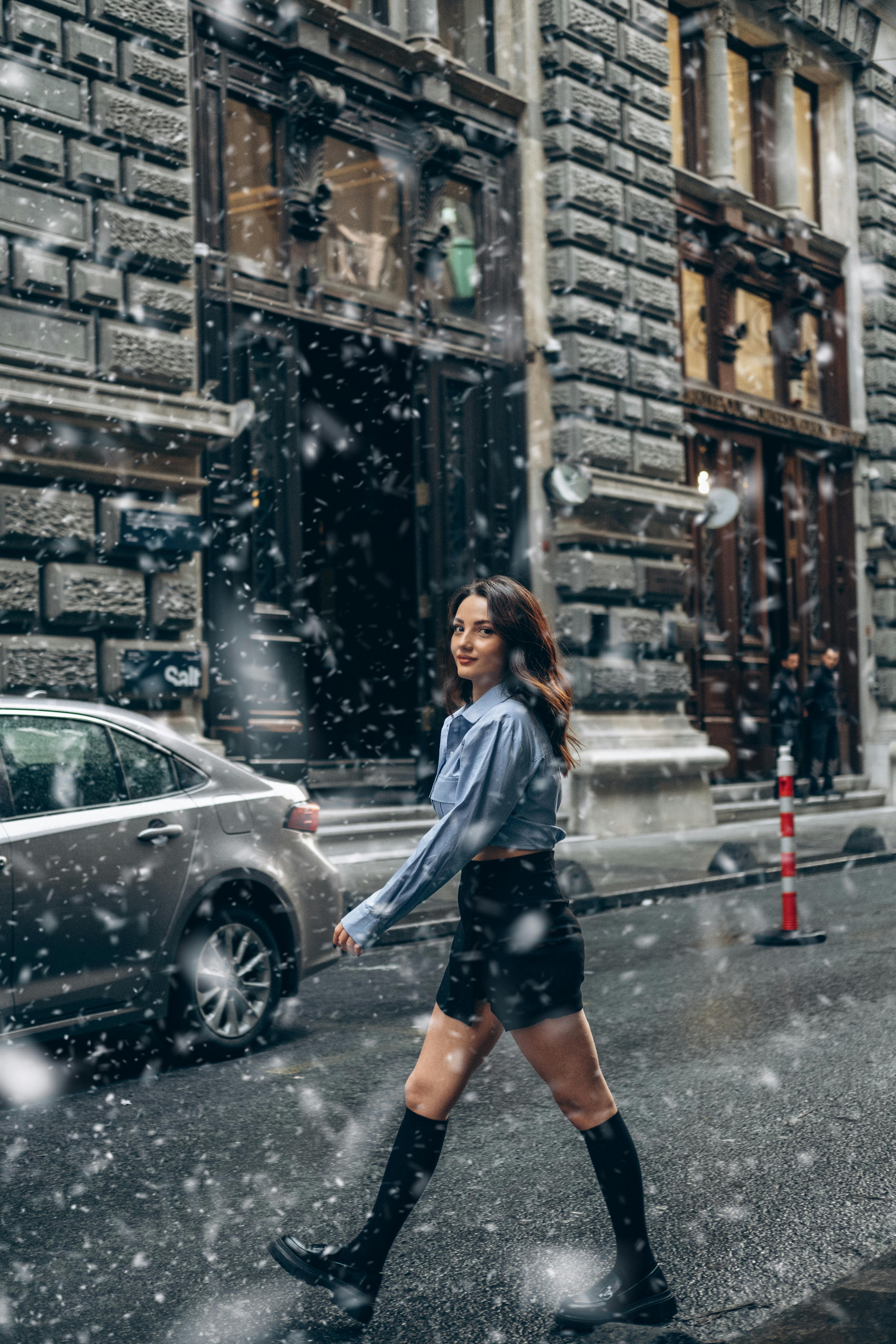 一位身穿蓝色上衣的女性在土耳其一条白雪皑皑的街道上行走，将时尚与城市冬季氛围融为一体