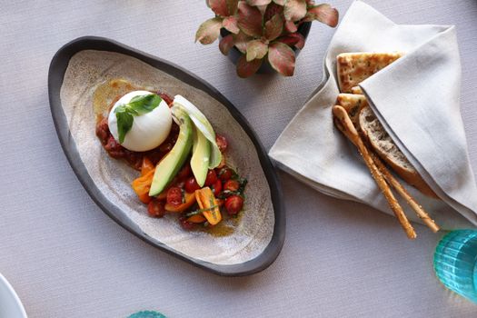 A delicious avocado and burrata salad with colorful cherry tomatoes on a stylish plate.