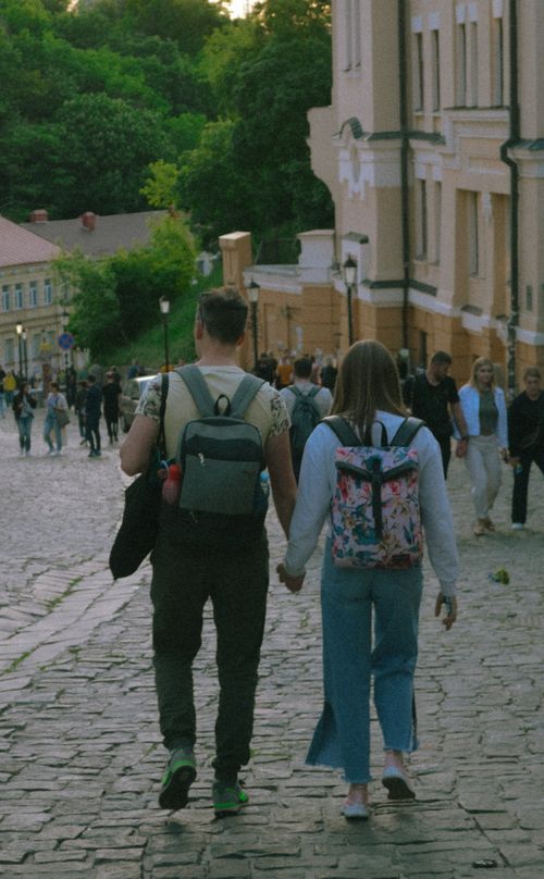 Free Couple holding hands while walking down a cobblestone street in Kyiv, Ukraine, surrounded by historic buildings. Stock Photo