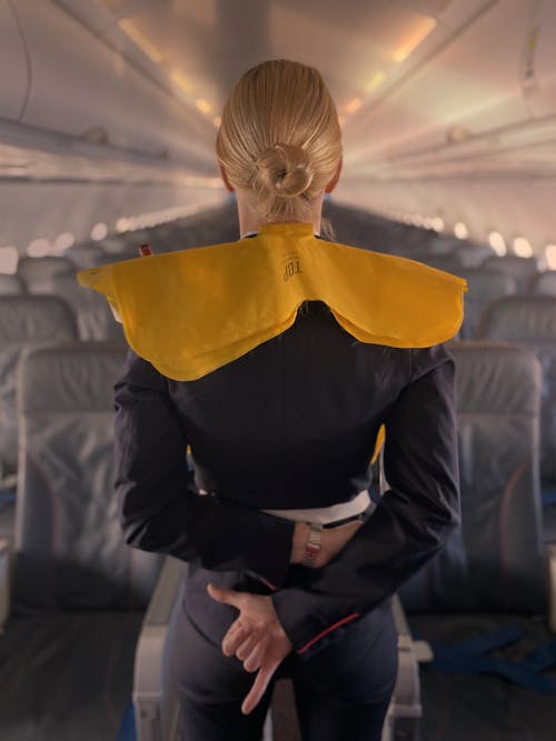 Free Stewardess in Life Jacket in Front of Empty Seats Stock Photo