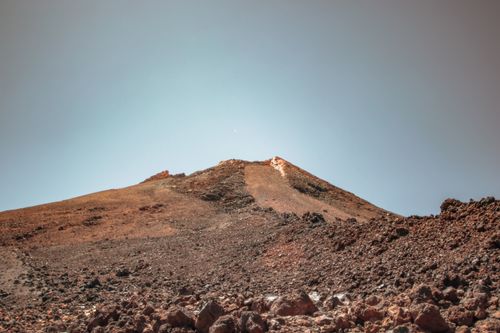 Free A stark, rocky mountain under a clear blue sky with arid terrain, showcasing nature's rugged beauty. Stock Photo