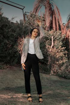 Elegant woman posing in a natural setting, showcasing modern fashion style with confidence.