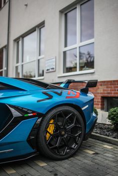 Sleek blue sports car parked next to a modern structure, showcasing luxury and performance.