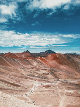 Stunning aerial view of a colorful desert landscape with mountains under a clear blue sky.