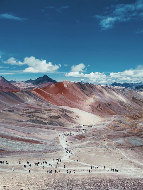 Stunning view of a colorful mountain landscape with hikers on a trail under a vivid blue sky.