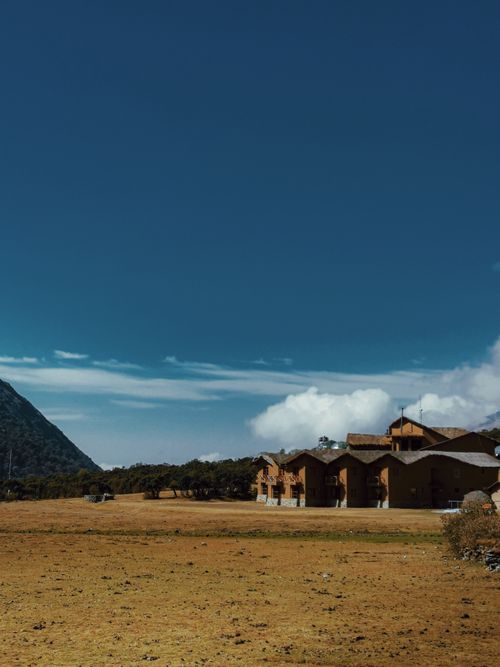 Free Rustic houses with clear blue sky and mountain backdrop, serene rural setting. Stock Photo
