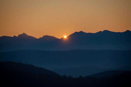 Stunning sunrise over mountain range with warm hues and silhouettes.