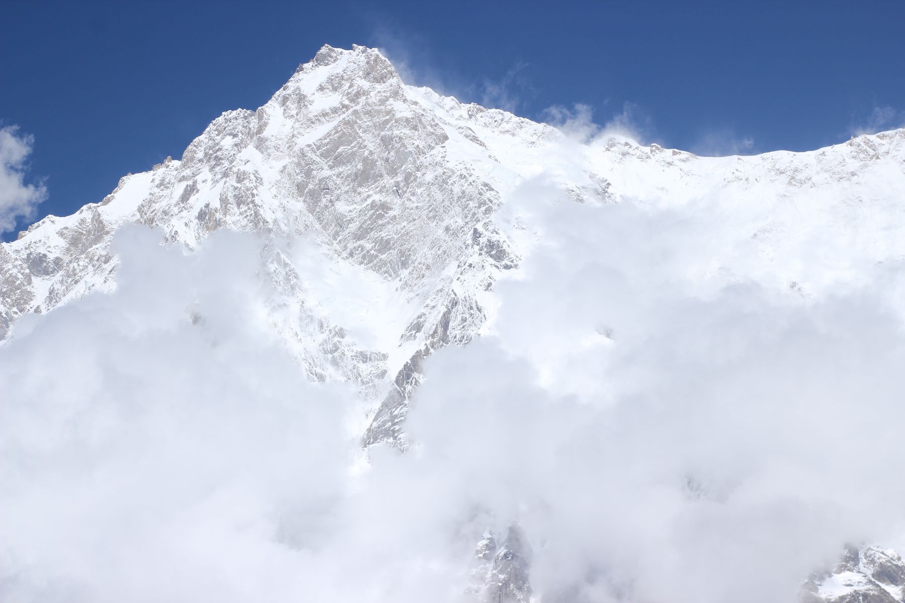 Majestic view of Nanga Parbat's snow-covered peak enveloped by clouds in Pakistan.