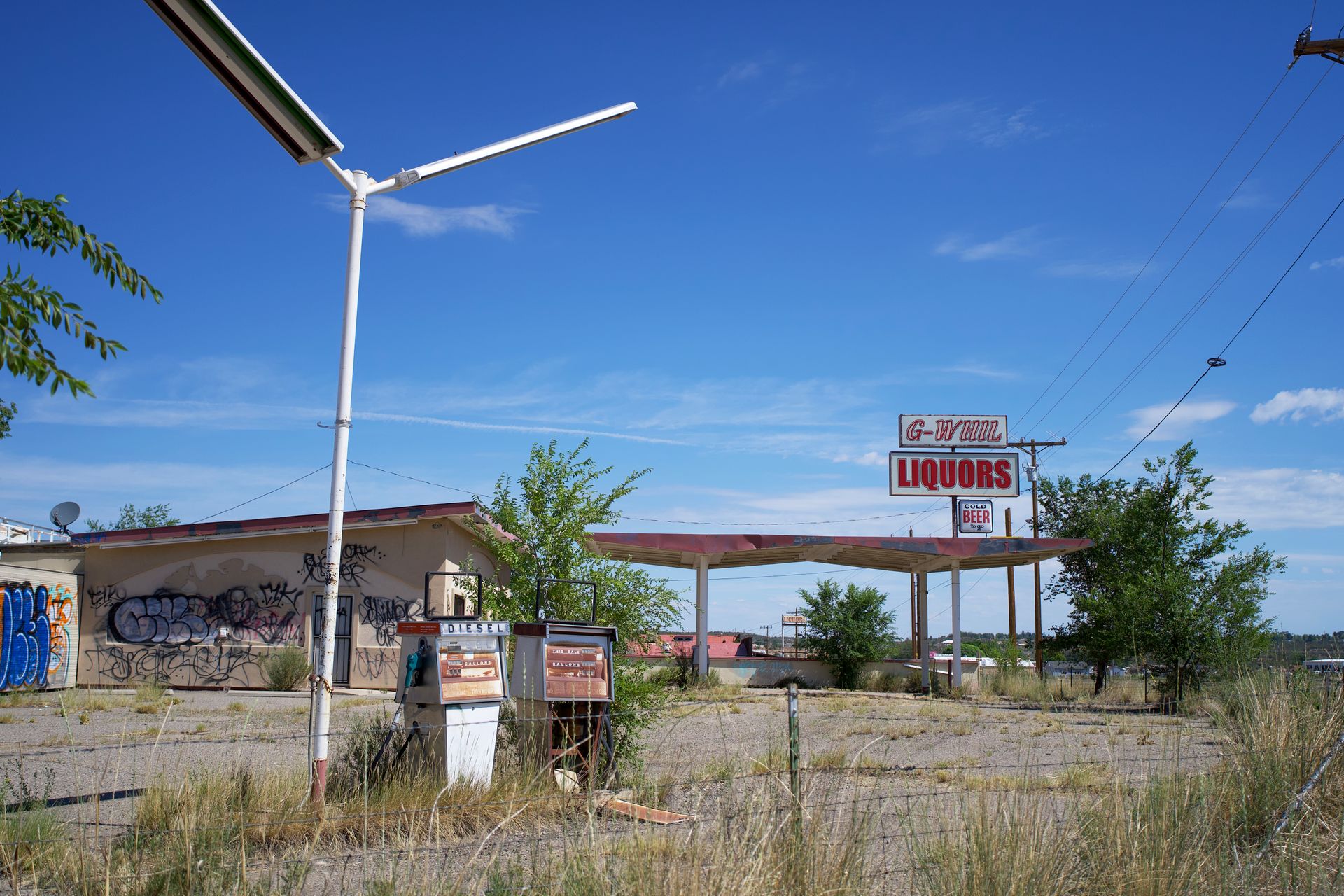 Explore the decay of an abandoned gas station adorned with graffiti under a clear blue sky.