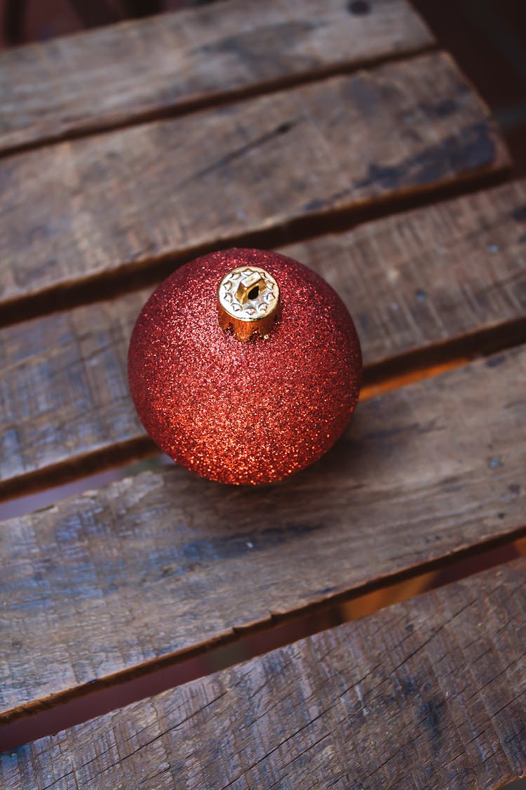 A Christmas Ball Covered With Glitters On Wooden Surface 