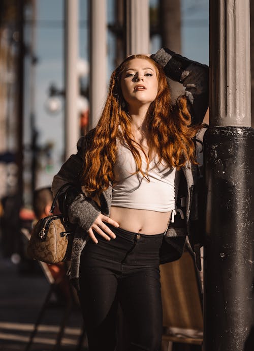 A Woman in a Crop Top Leaning on a Pillar