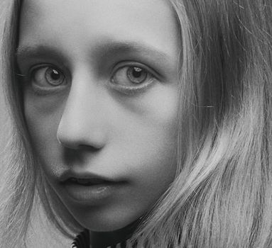 Thoughtful black and white close-up portrait of a young girl with long hair.