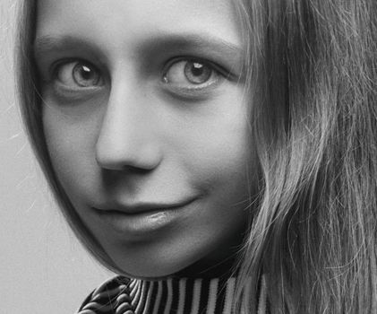 Close-up black and white portrait of a smiling young woman with expressive eyes.