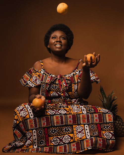Woman in Dress Juggling Orange Fruits