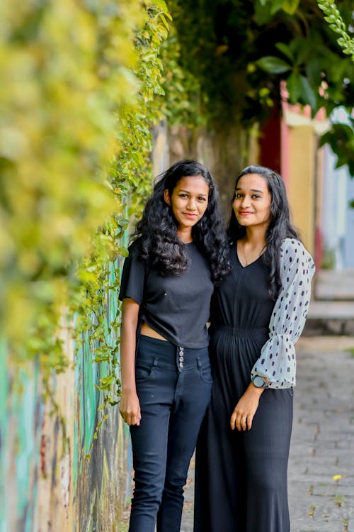 Women Posing near a Wall Full of Hanging Plants