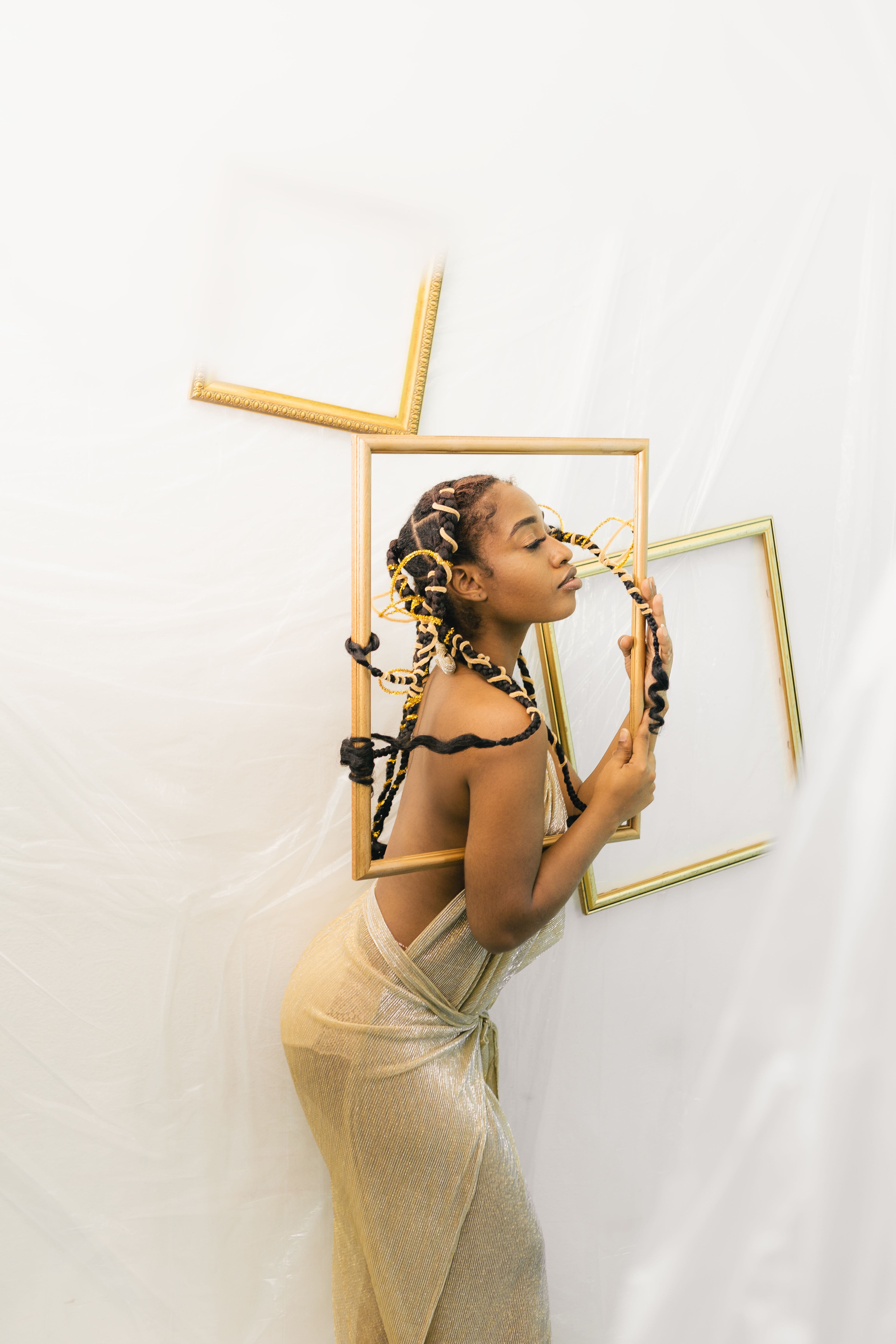 Elegant portrait featuring a woman with braided hair surrounded by empty frames, showcasing artistic expression.