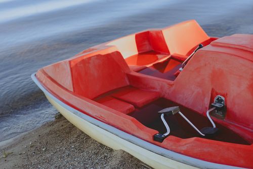 Free Red pedal boat by the beach, ideal for summer leisure and water activities. Stock Photo