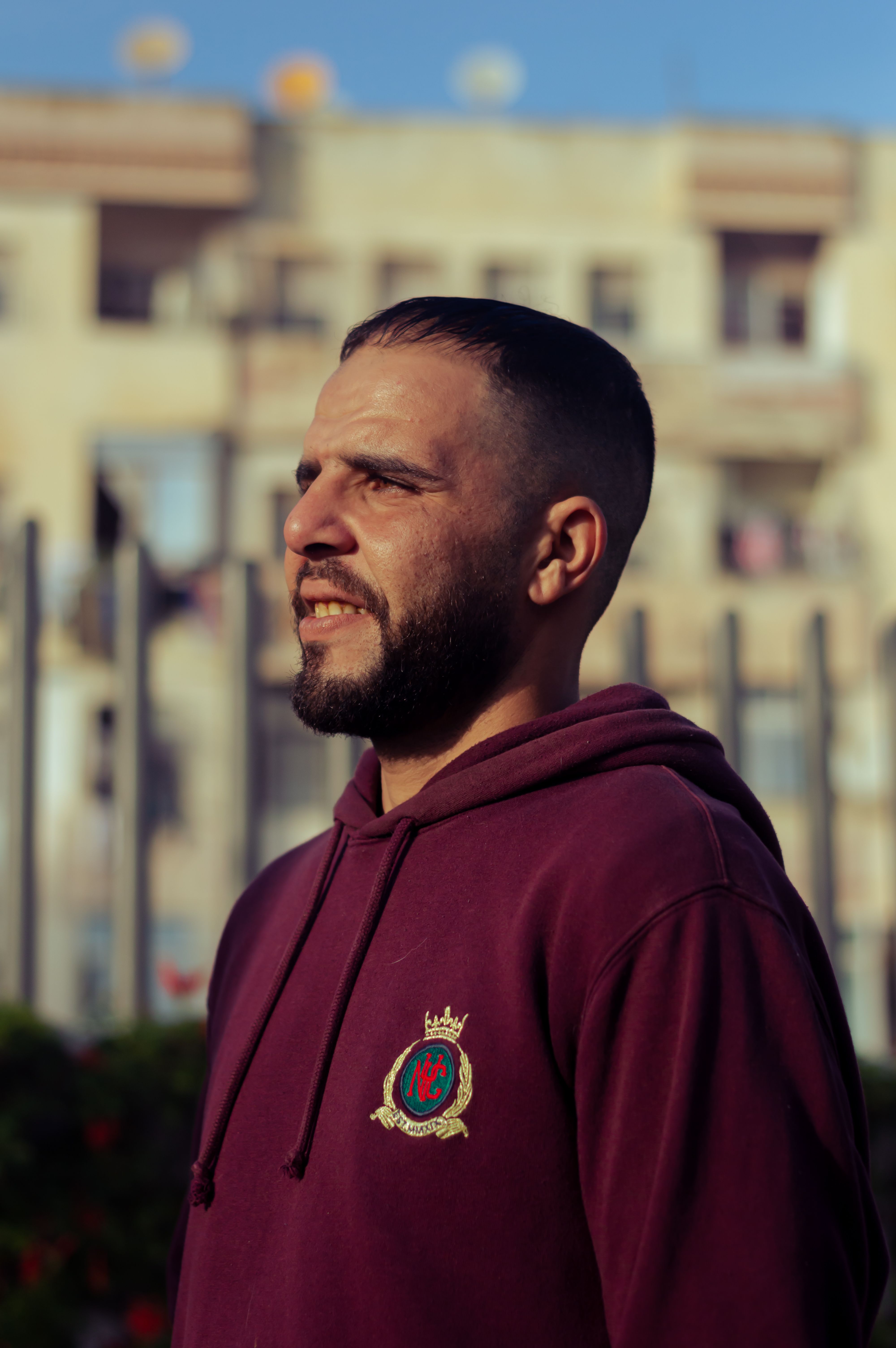 A bearded man wearing a hoodie in Casablanca, Morocco, with a thoughtful expression.