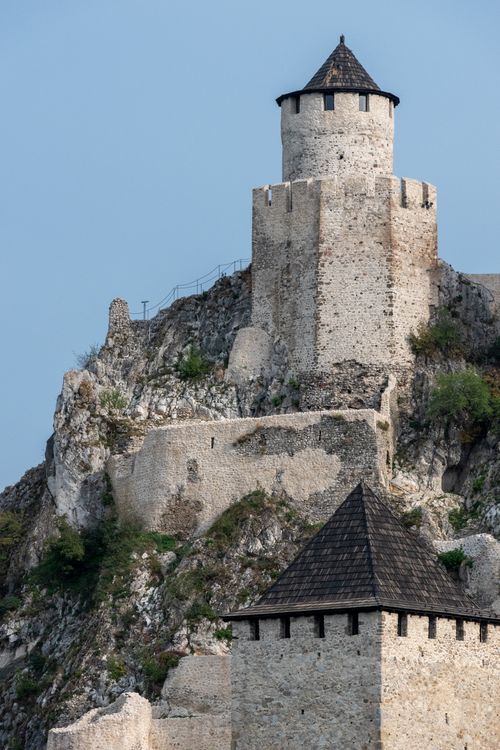 Free A historic stone fortress tower on a rocky hill under a blue sky, showcasing medieval architecture. Stock Photo