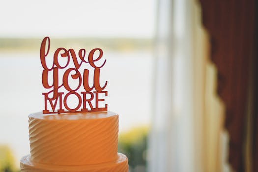 A beautifully decorated wedding cake featuring a 'love you more' topper in a softly lit setting.