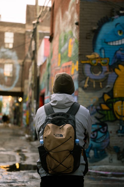 Man with Backpack against Urban Architecture in Graffiti