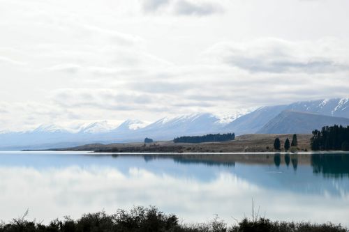 Free Serene view of Lake Tekapo and snow-capped mountains reflecting in calm waters, New Zealand. Stock Photo