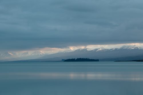 Free Peaceful lake with snow-covered mountains and cloudy sky. Stock Photo