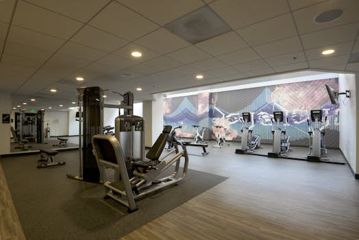 Spacious modern gym with exercise equipment and vibrant wall art for a dynamic workout environment.