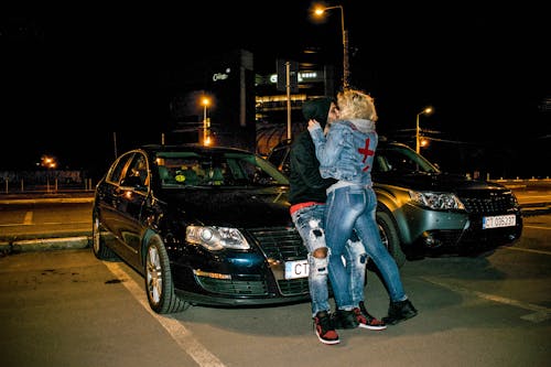 Free Couple Kissing Beside Black Volkswagen Passat B6 Sedan during Nighttime Stock Photo
