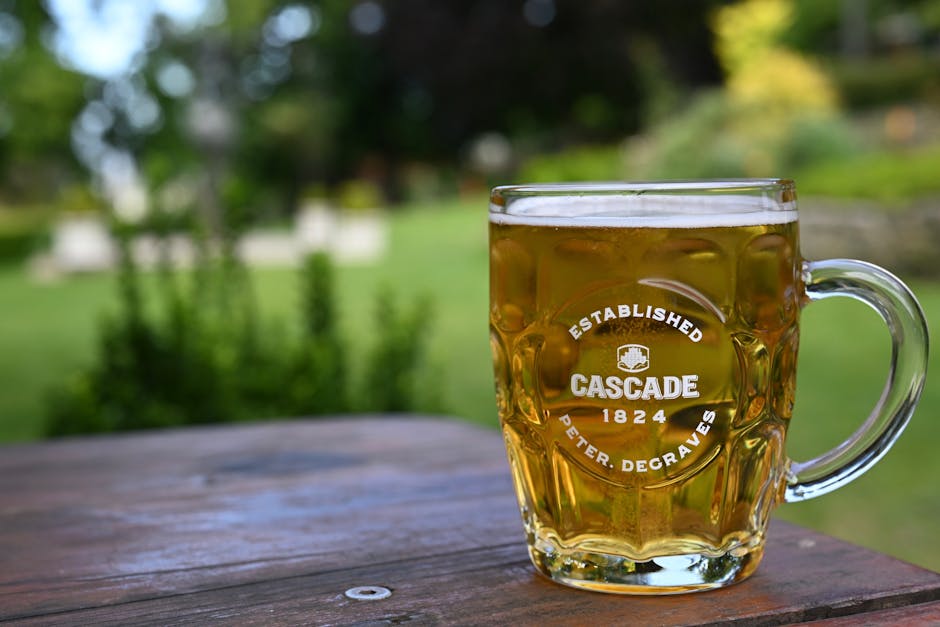 A clear glass of Cascade beer on a wooden table in a lush South Hobart garden.