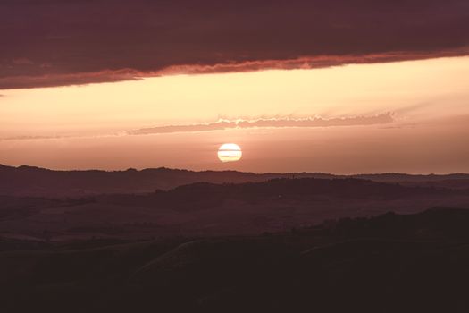 Stunning sunset with vibrant colors over a rolling hills landscape, perfect for peaceful nature scenes.