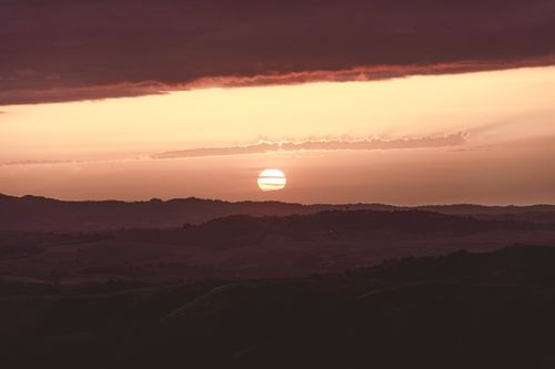 Free Stunning sunset with vibrant colors over a rolling hills landscape, perfect for peaceful nature scenes. Stock Photo