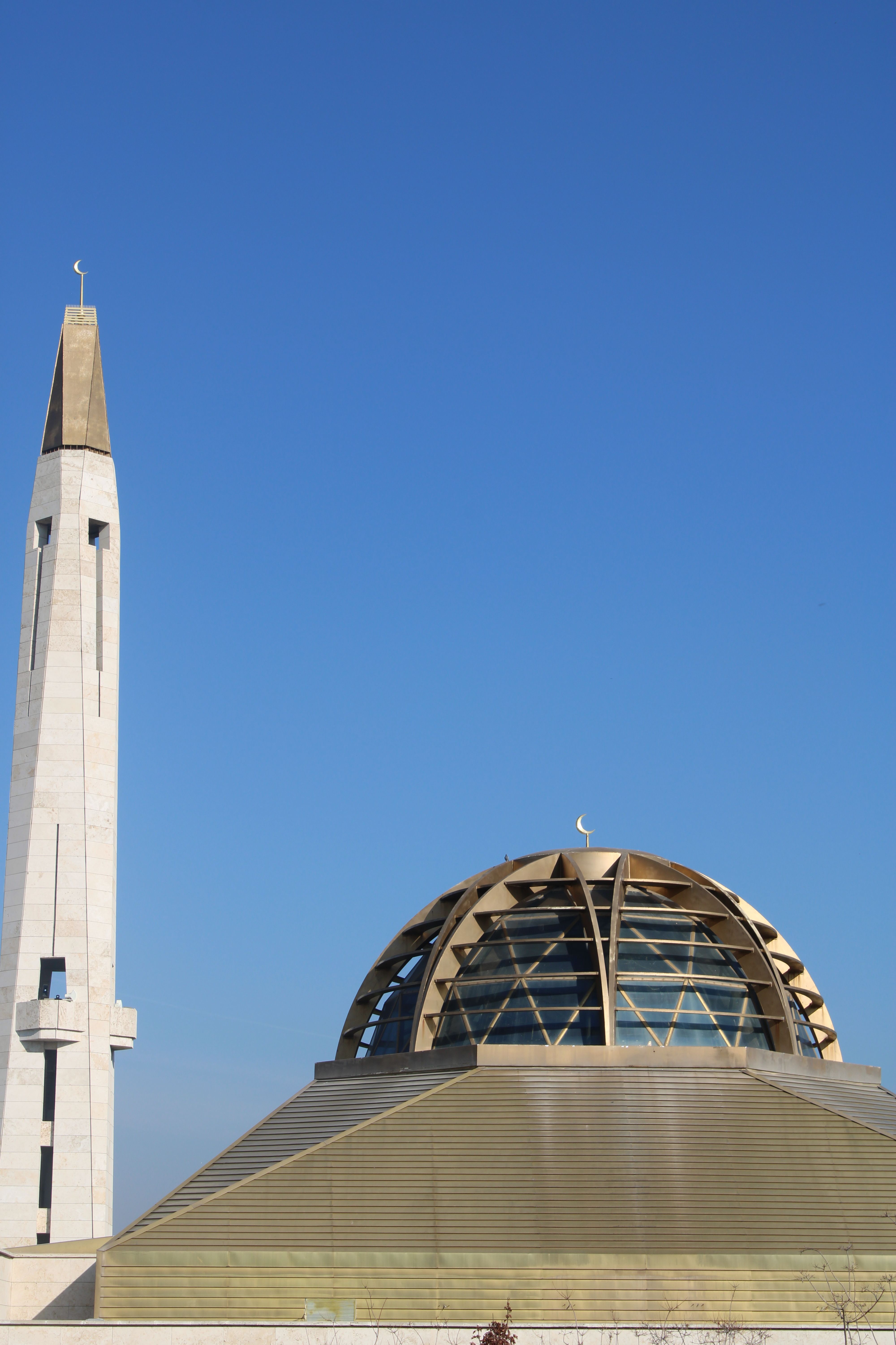 Striking view of a mosque with a modern dome and minaret under a clear blue sky.