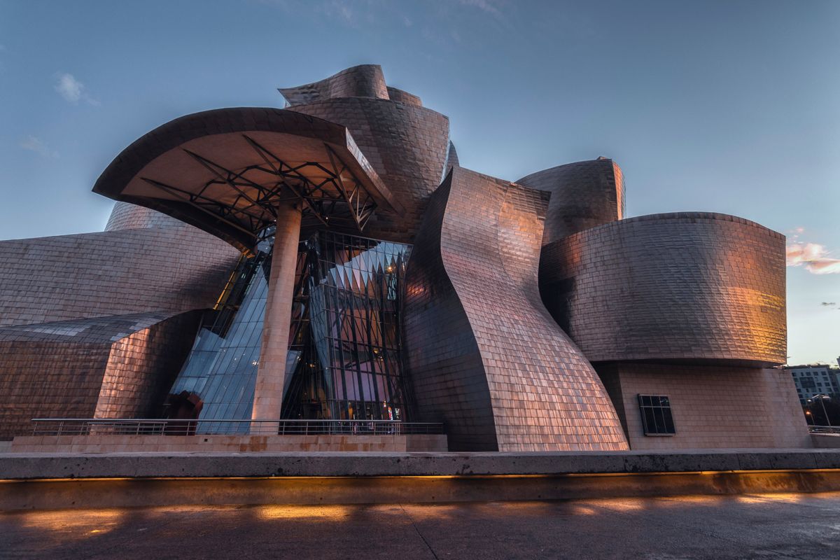 Muzeul Guggenheim din Bilbao, cu fațada ondulată de titan, în lumina serii