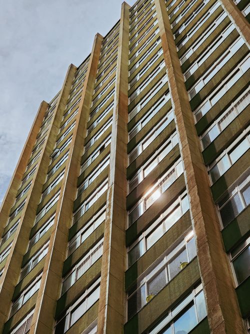 Free Low-angle view of a modern high-rise building showcasing its vertical glass facade and architectural design. Stock Photo