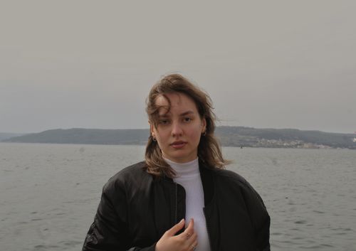 Free Outdoor portrait of a woman by the sea on a gray, windy day in Çanakkale, Turkey. Stock Photo