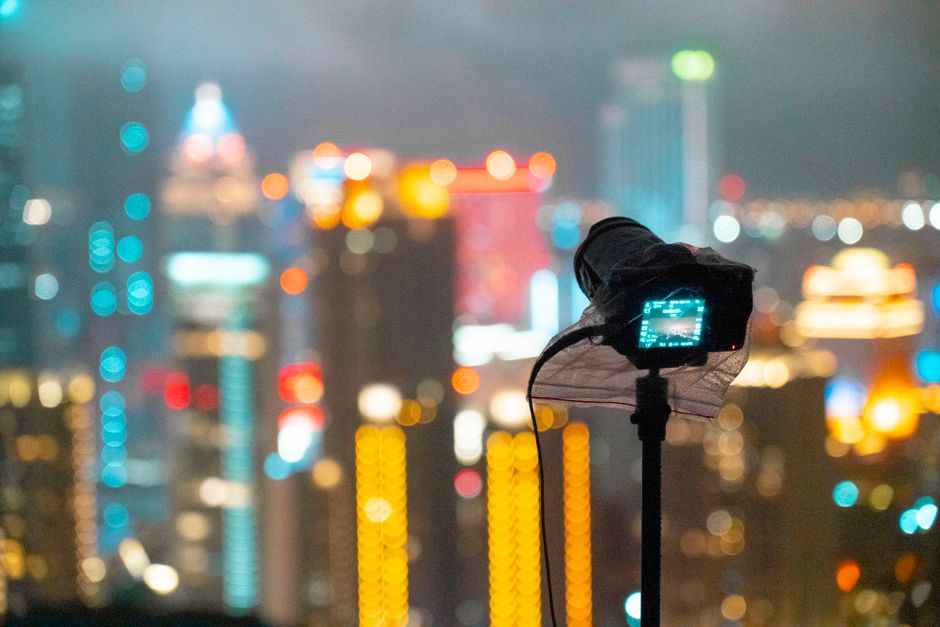 A vibrant cityscape of Taipei at night with a camera capturing the illuminated skyline.