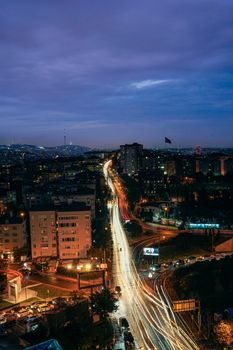 Capture of a bustling city with light trails under a twilight sky, showcasing urban energy.