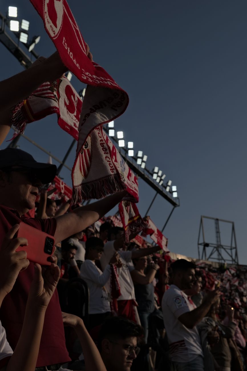 Crowd of diverse fans cheering loudly at a sport event in Seville, Spain.