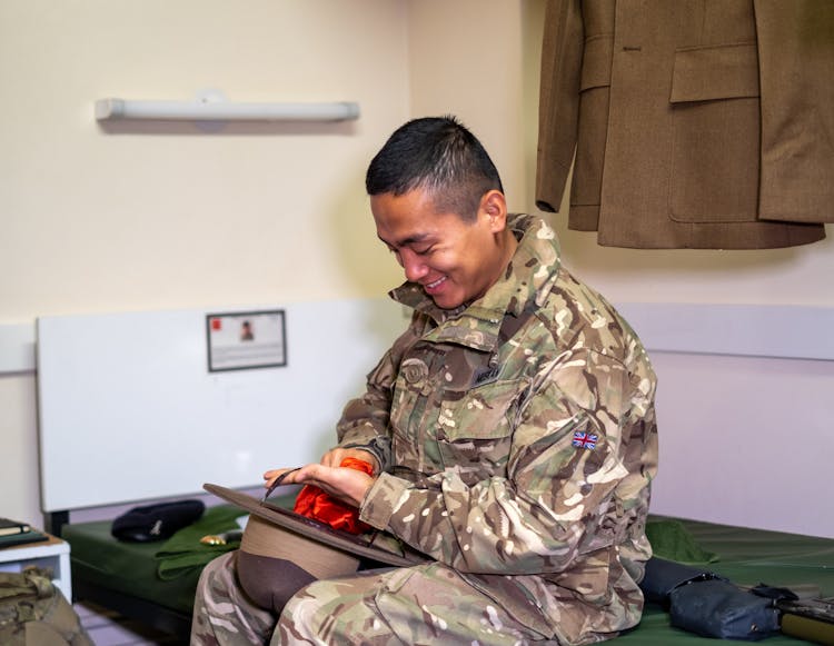 A Military Man Sitting On A Bed