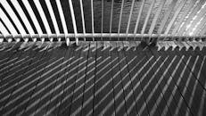 黑白图像中，木板上桥梁栏杆投下了复杂的阴影图案