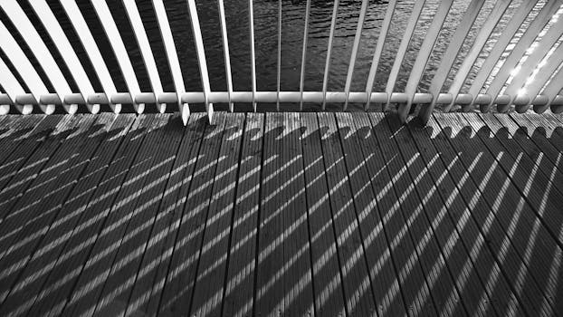 黑白图像展示了桥梁栏杆在木板上投射出的复杂阴影图案