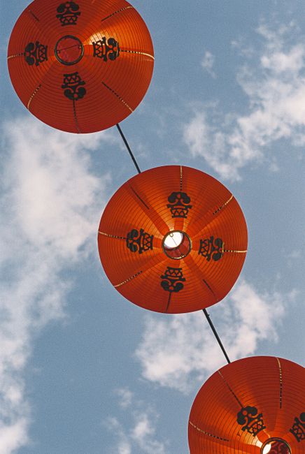 Vibrant red lanterns hanging against a clear blue sky in Bangkok, Thailand.